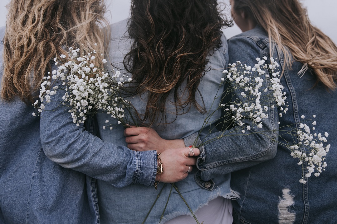 Groupe d'amies qui tiennent des fleurs dans leurs mains