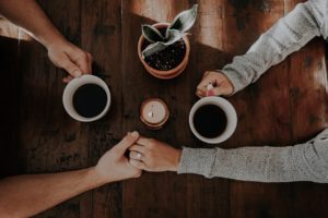 MAINS D'UN COUPLE QUI BOIT UN CAFE