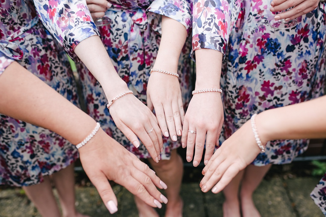 Quatre mains de demoiselles d'honneur qui portent le même bracelet