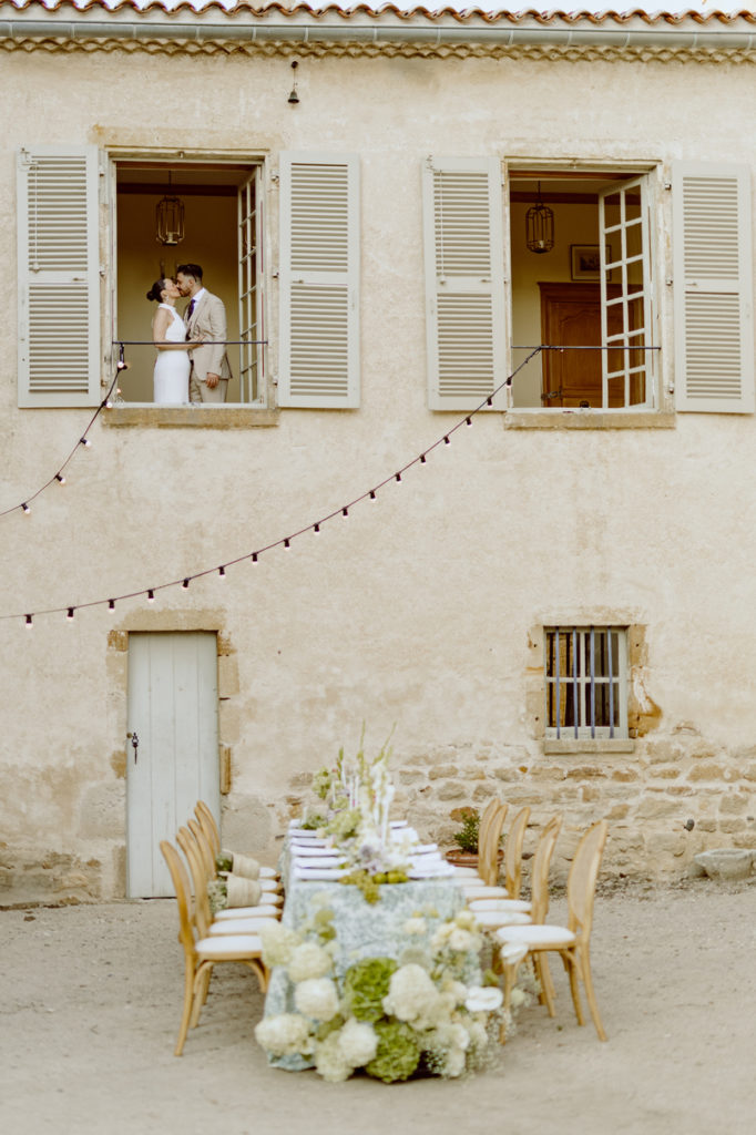 couple de mariés à la fenêtre d'un domaine